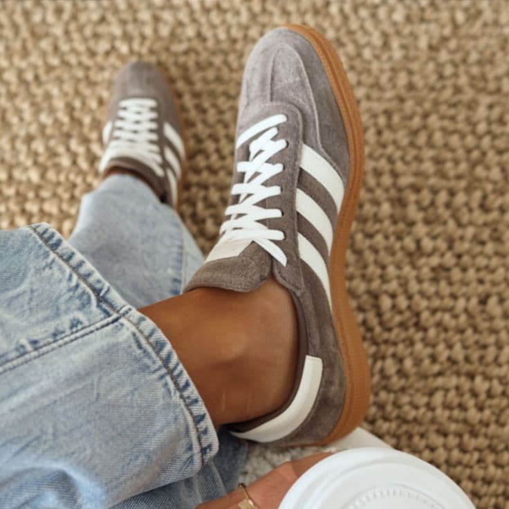 Top-down view of grey Adidas Gazelle sneakers on textured carpet